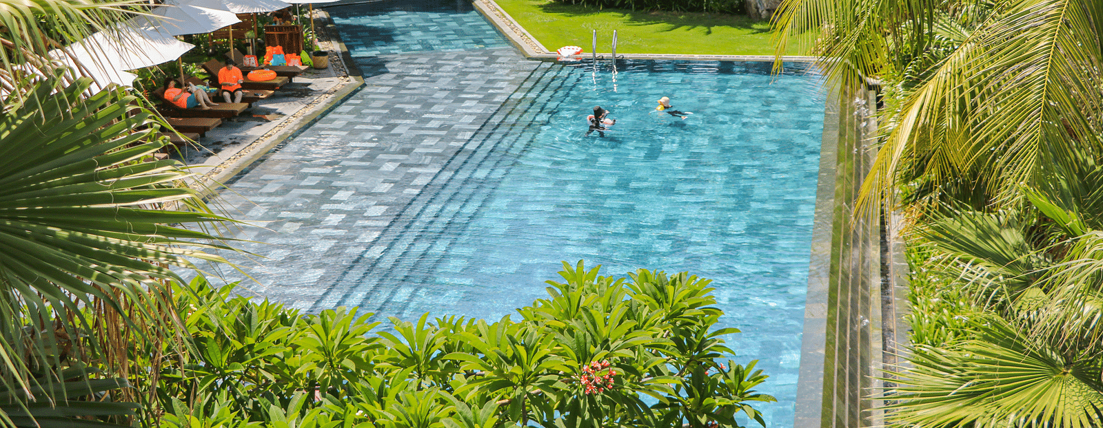 An image showcasing the pool at our resort with people enjoying a swim during a sunny day - Alibu Resort Nha Trang