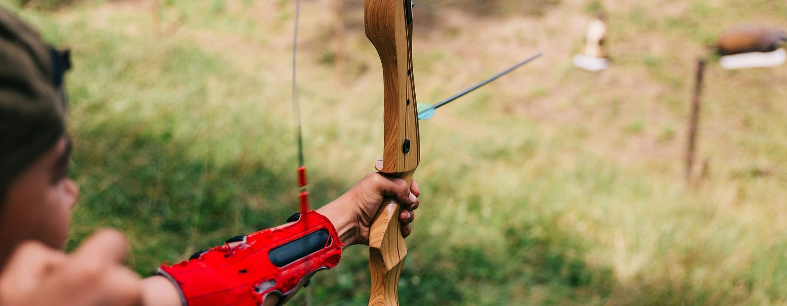 A child practicing archery in an open field.
