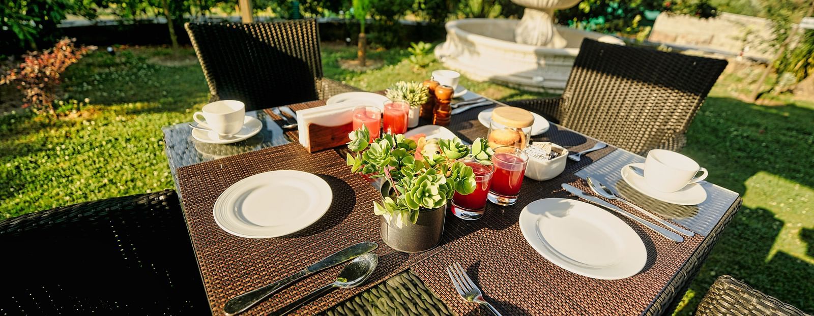 A picture of Outdoor breakfast setup with a table, chairs, and a beautiful garden view.