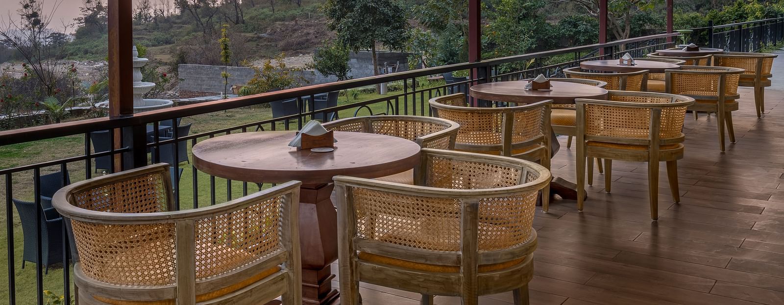 An image of Outdoor seating area with a view of lush trees and mountains at Atman, dharamshala.