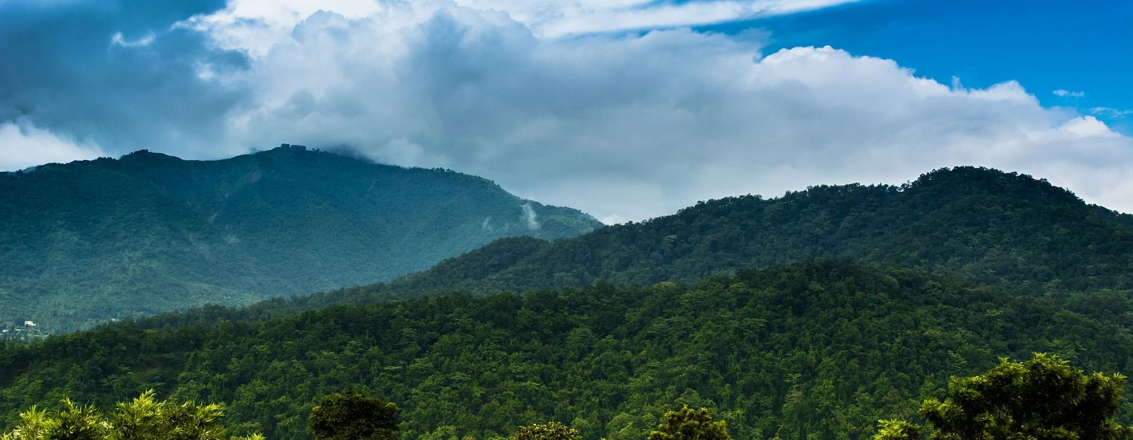 A wide view of mountains with a sky with scattered clouds in the background