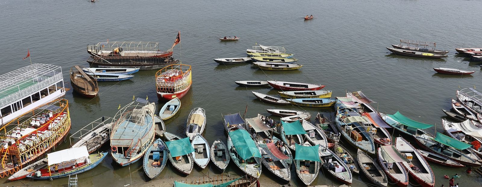 An image featuring numerous boats docked along the banks of the Ganga River in Varanasi, with several boats lined up on the water.