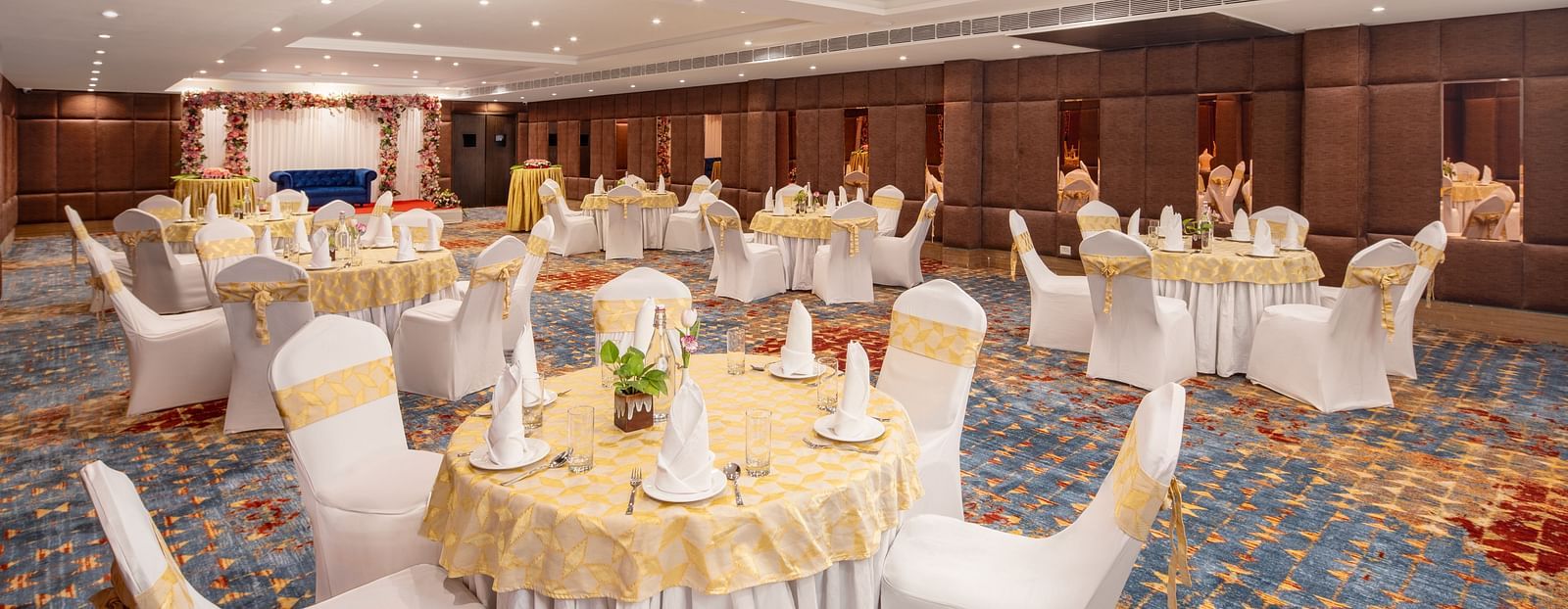 An image of a banquet hall with several chairs and table sets spread out - Brij Eternity, Vrindavan