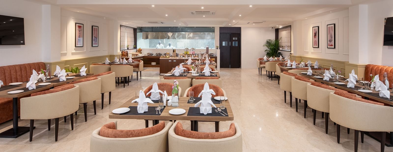An image of a dining space with sofa chairs, centre table with hand towels and cutlery, and a buffet served at one corner - Brij Eternity, Vrindavan