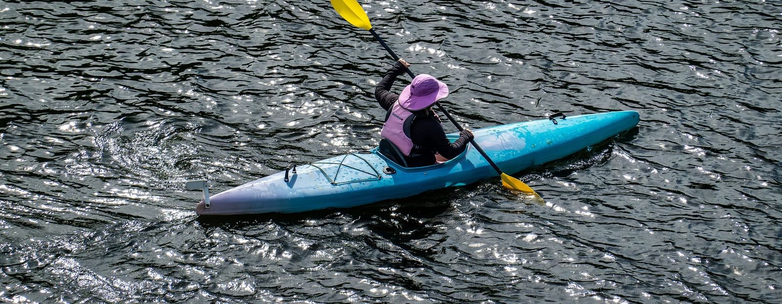 A solitary person kayaking in a waterbody as seen from above