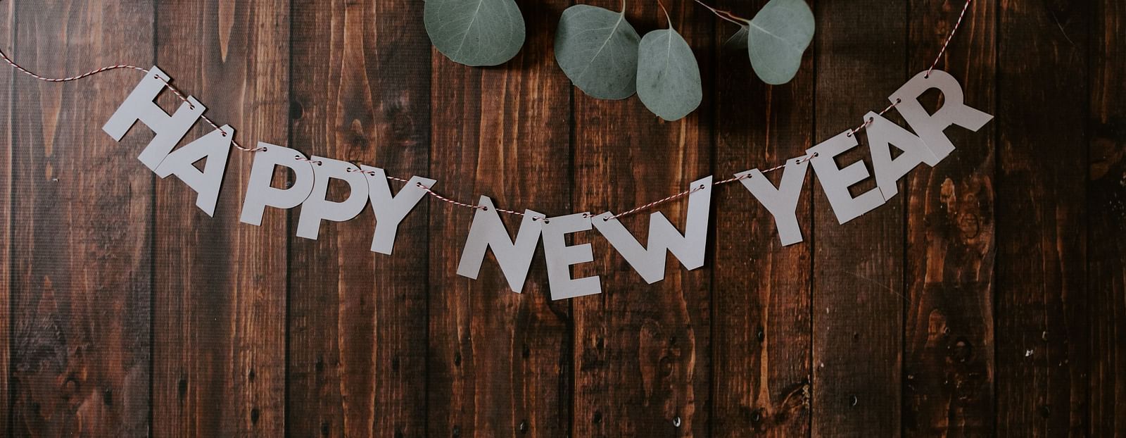the words happy new year written on a wooden table with leaves on the top