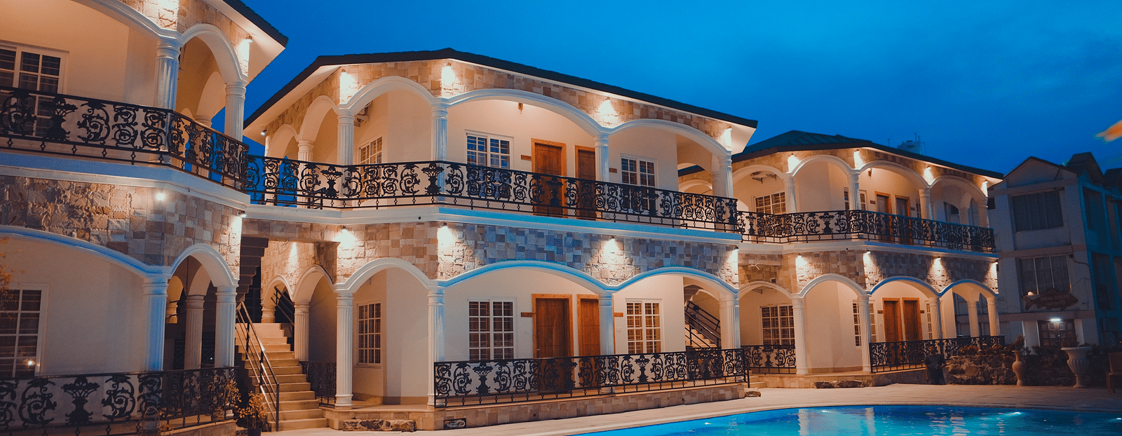 facade image of our hotel in birbhum in the late evening with a beautiful view of the swimming pool in the foreground