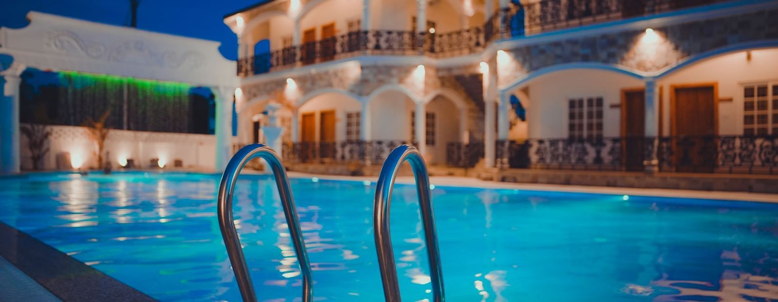 image featuring the stairs leading inside the swimming pool with the facade of dip holidays in the background