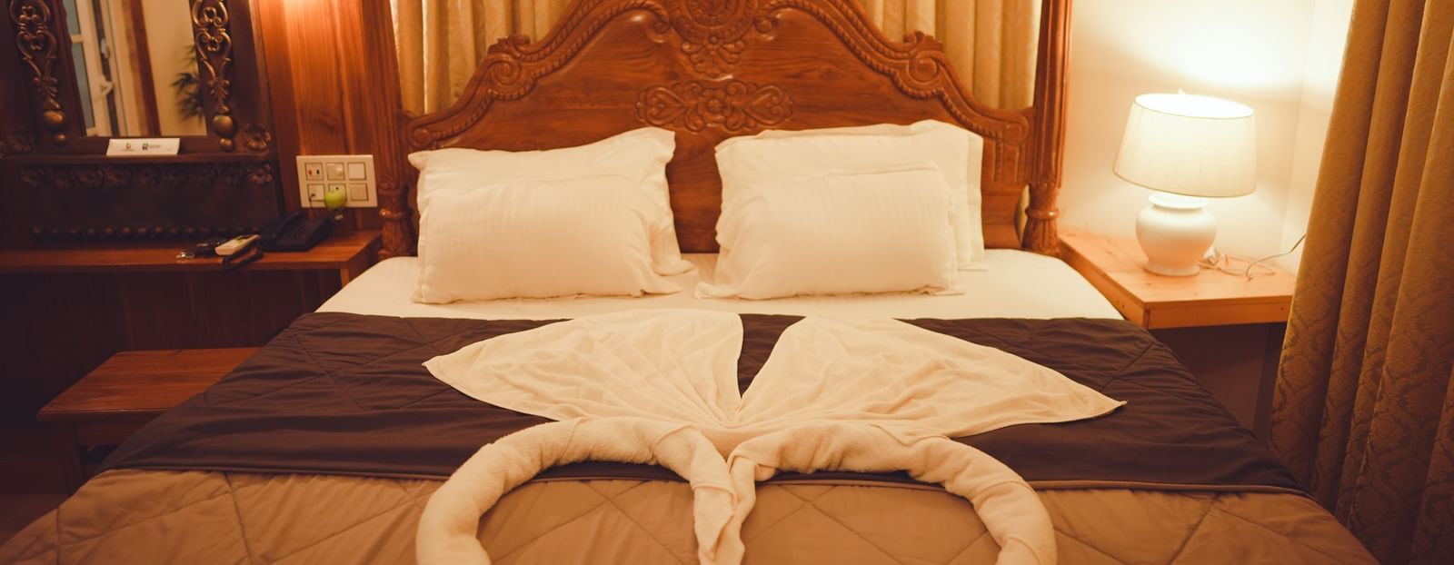 front view of the king size bed with two pillows kept at the far end of the room with a table lamp kept on the side table