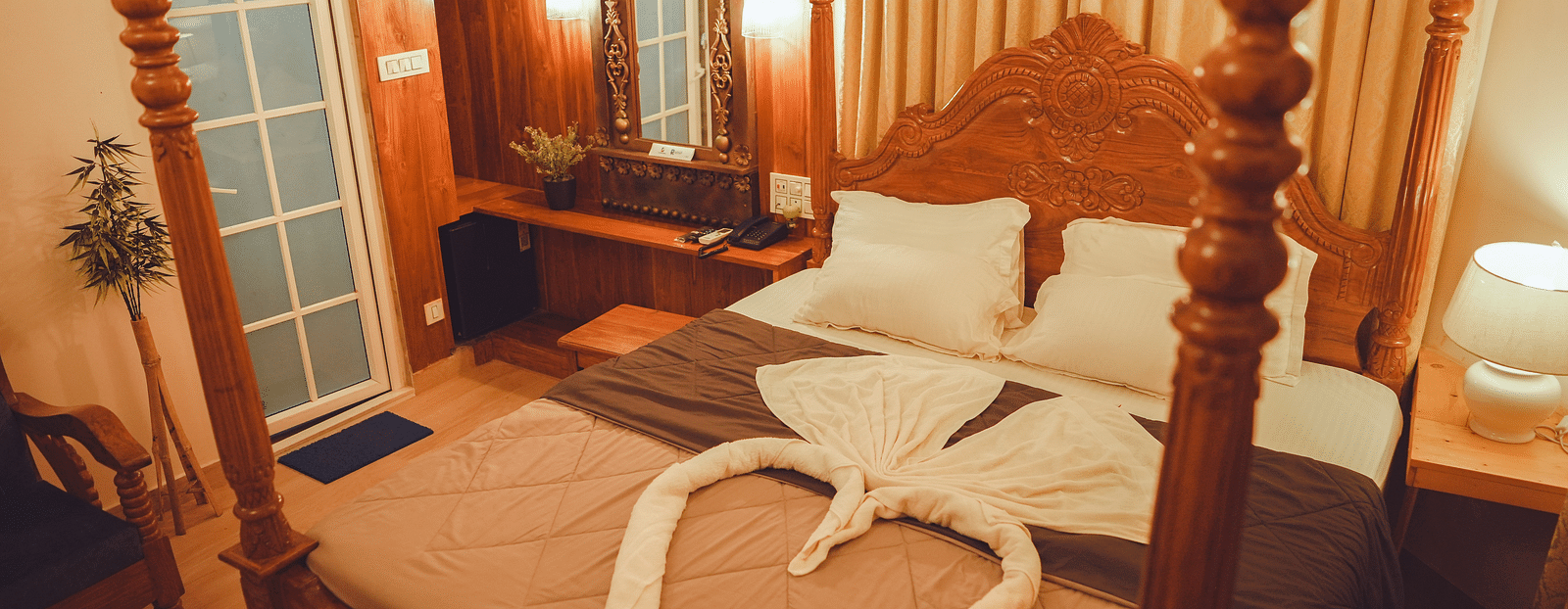 image of a cosy bedroom featuring a king size bed with a bed side table lamp brightening the room with warm lighting