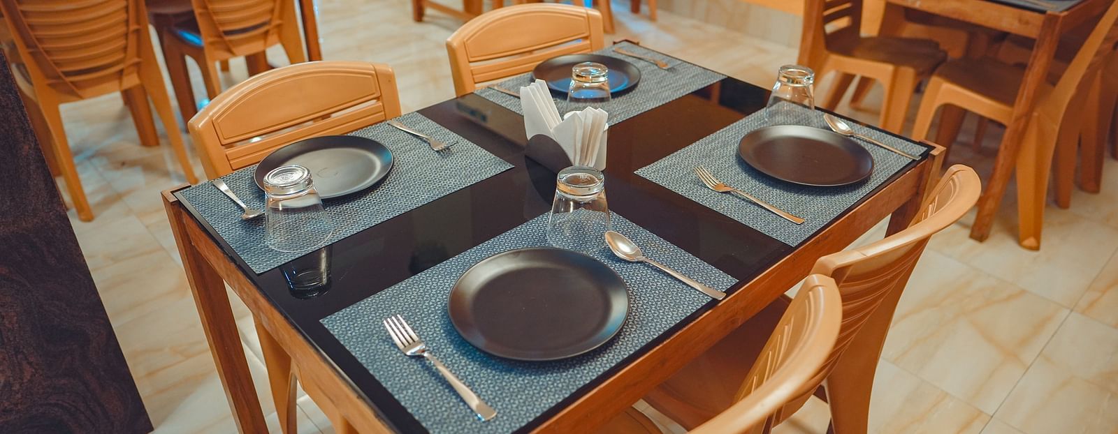 image of a four seater dining area with plates and cutlery well placed on the dining table - Dip Holidays, Birbhum