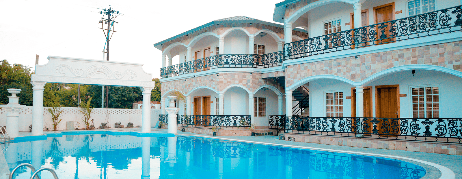 facade image of dip holidays featuring a vast swimming pool right in front of the building