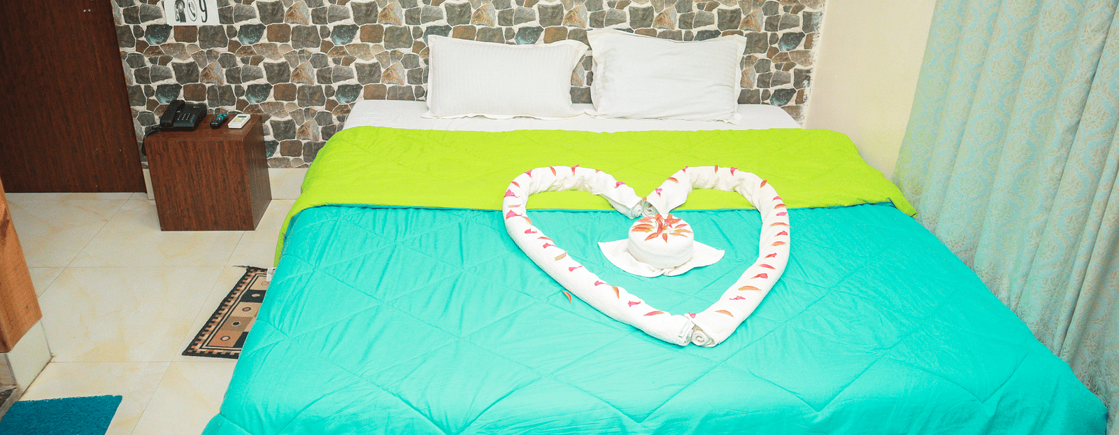 image of a plush king size bed with a teal and green coloured comforter spread across the bed