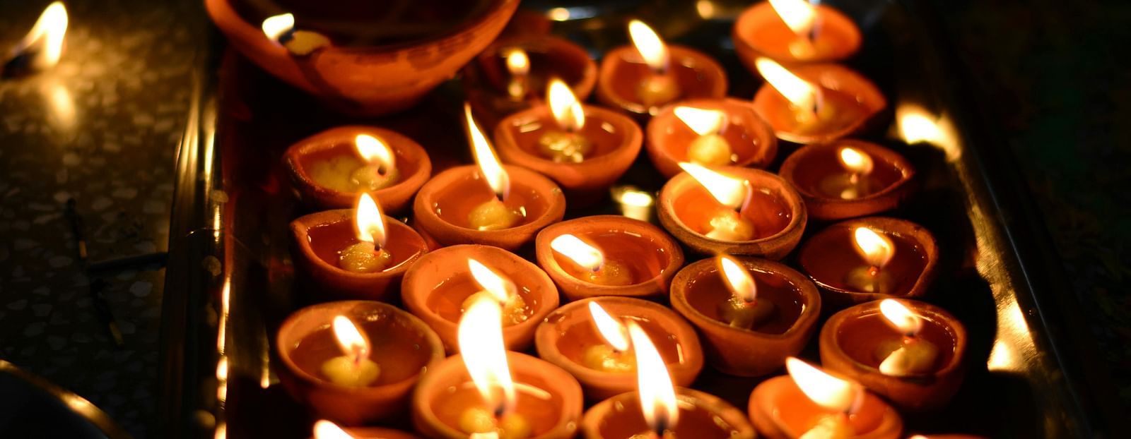 image of several earthen oil lamps lit up in a dark space