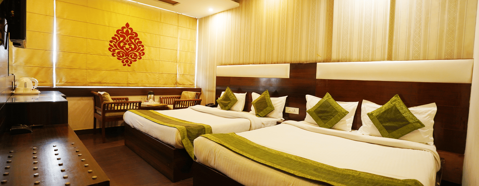 A landscape view of Family room with two King-sized beds with cushions and pillows, curtains rolled down, AC and a designer ceiling with fan. 