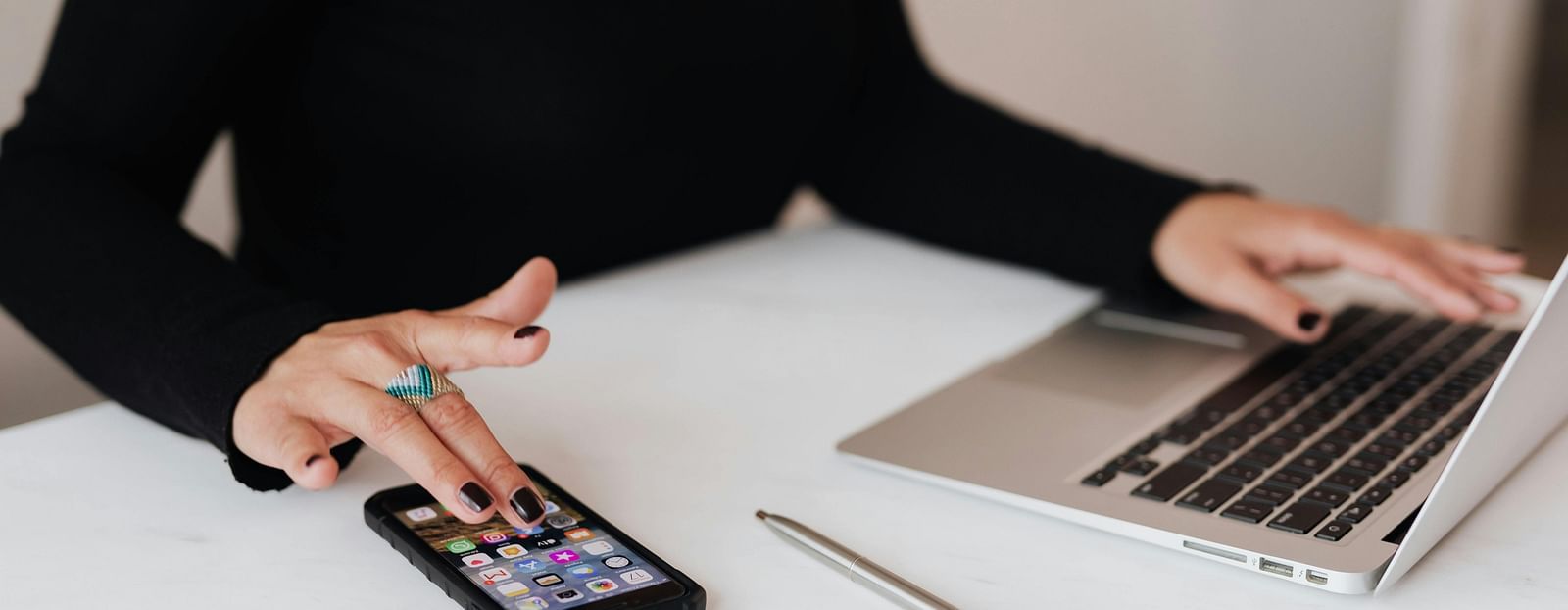 Image of a person with hands on a laptop and phone.