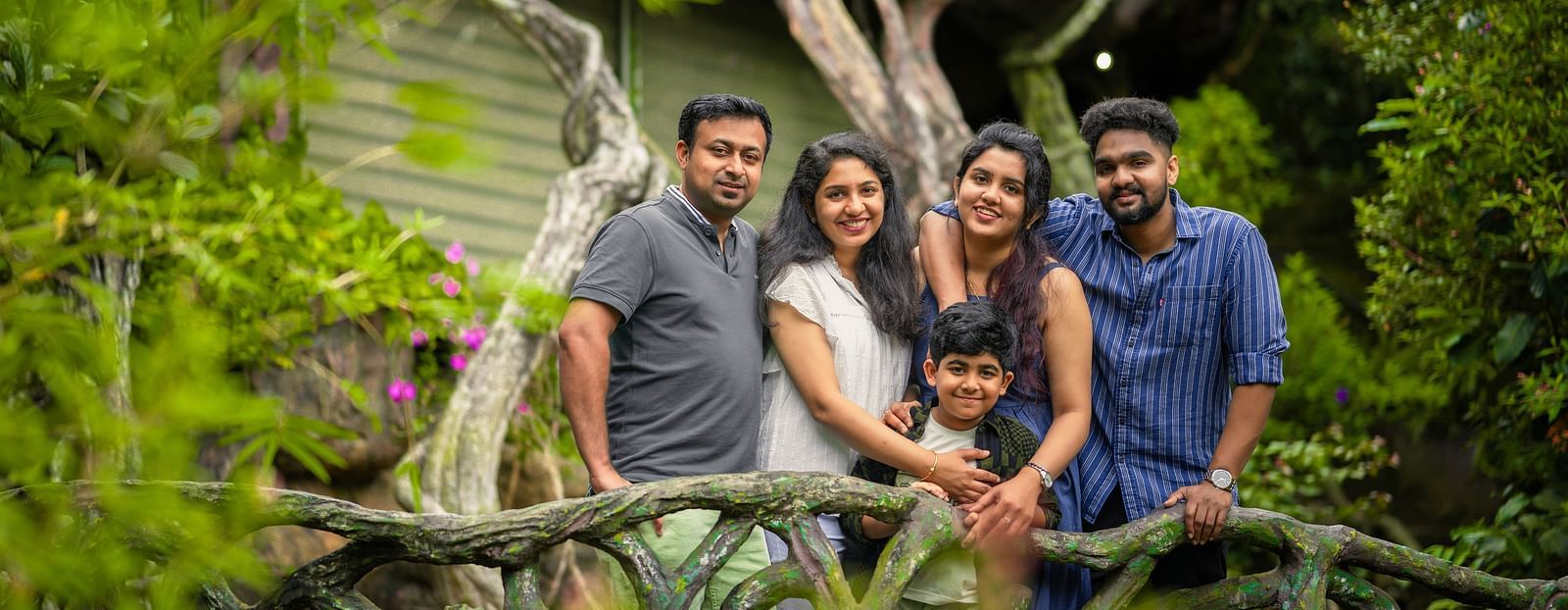 An image of five people posing  near a facade which is surrounded by trees - Parakkat hotel & resorts