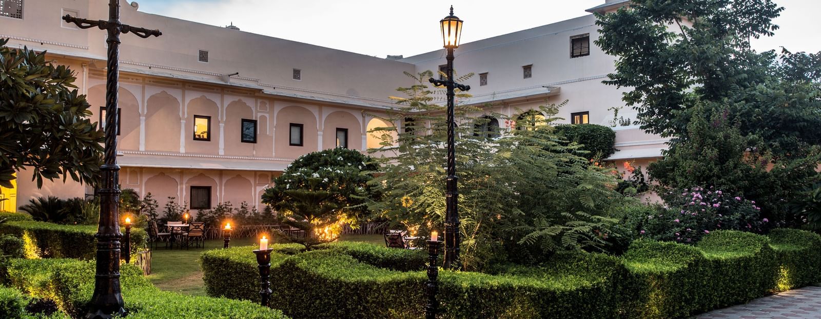An exterior view of Royal Heritage Haveli at dusk with illuminated pathways and landscaped gardens.