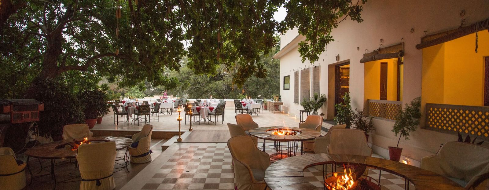 An outdoor patio or courtyard at Royal Heritage Haveli with tables and chairs, illuminated by lights, and a checked floor pattern.