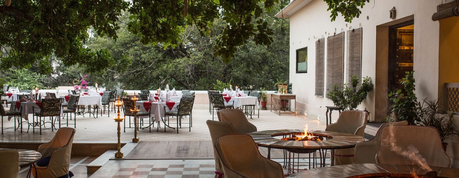 An outdoor patio area at Royal Heritage Haveli with seating around a fire pit and a building in the background.