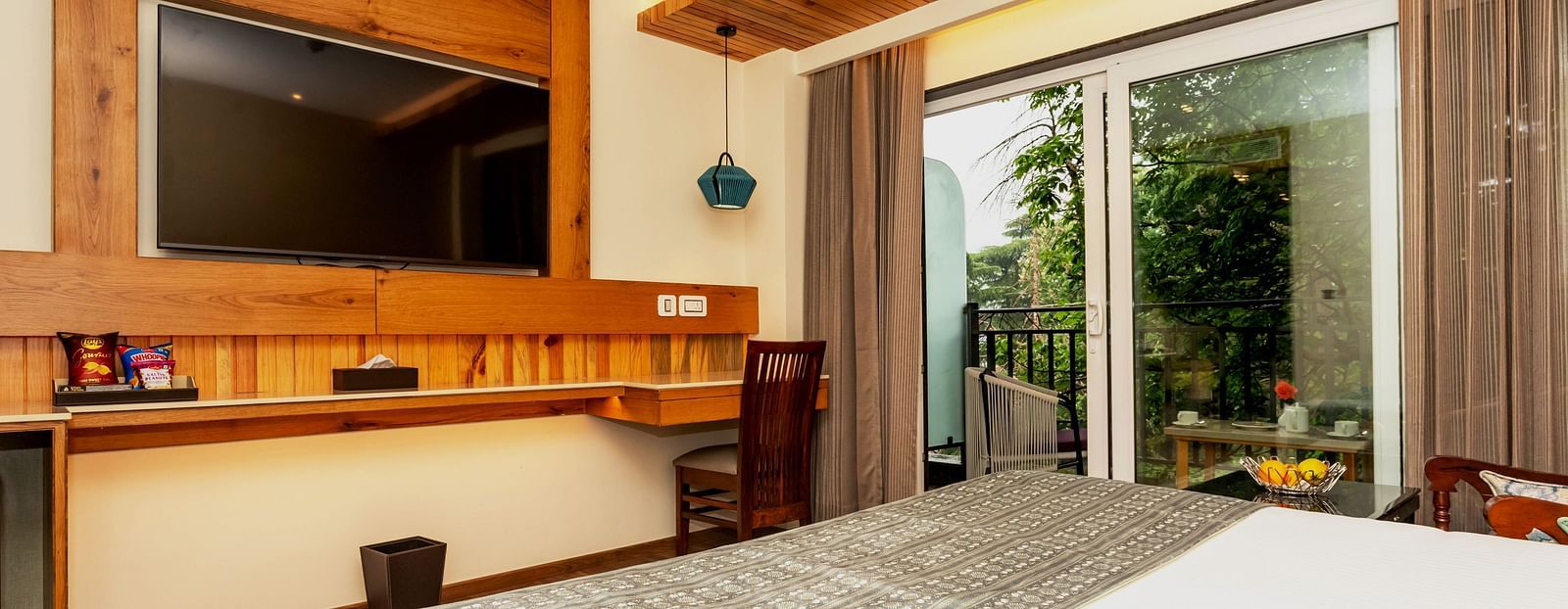 An image of a Superior Room with bed, flat screen TV, work desk and chair, and an expansive glass door leading to the balcony - The Belvedere Himalayan Retreat, McLeodganj