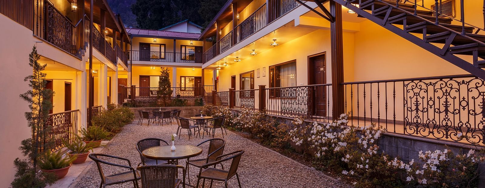 interior of the property with tables and chairs in clusters with flowers and plants on each side of the path - The Earl's Court, Nainital