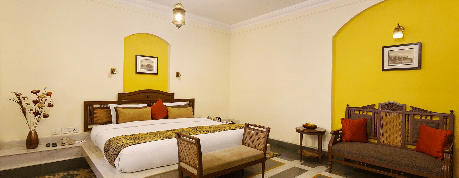 A Superior Room at The Haveli Hari Ganga in Haridwar features a comfortable bed and a cozy sitting area, offering a perfect blend of relaxation and style for guests during their stay.