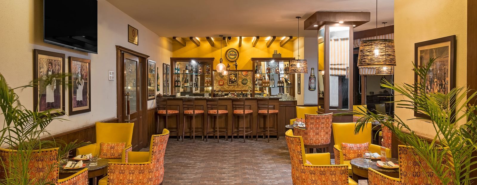 a view of clusters of chairs and tables with a bar counter at the end of the room - The Manor, Kashipur