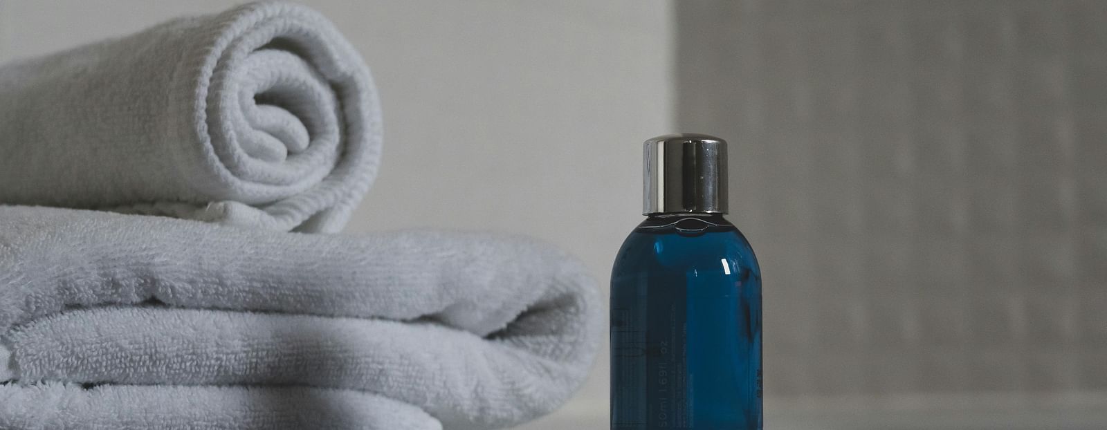 A shampoo bottle placed near neatly folded towels