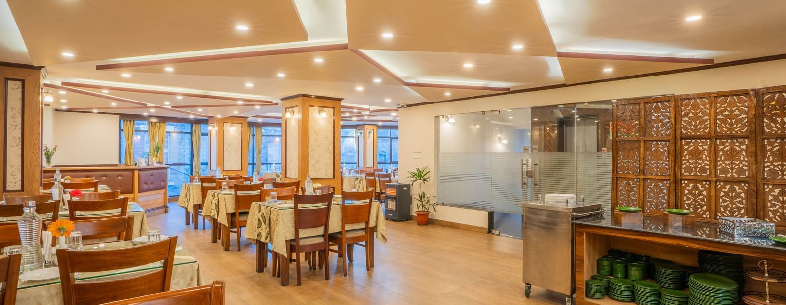 A bright and spacious hotel restaurant with tables, chairs, and a buffet counter at the Yashshree Jai Hotel & Banquet, Darjeeling.