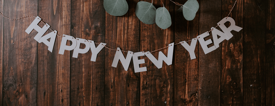 the words happy new year written on a wooden table with leaves on the top