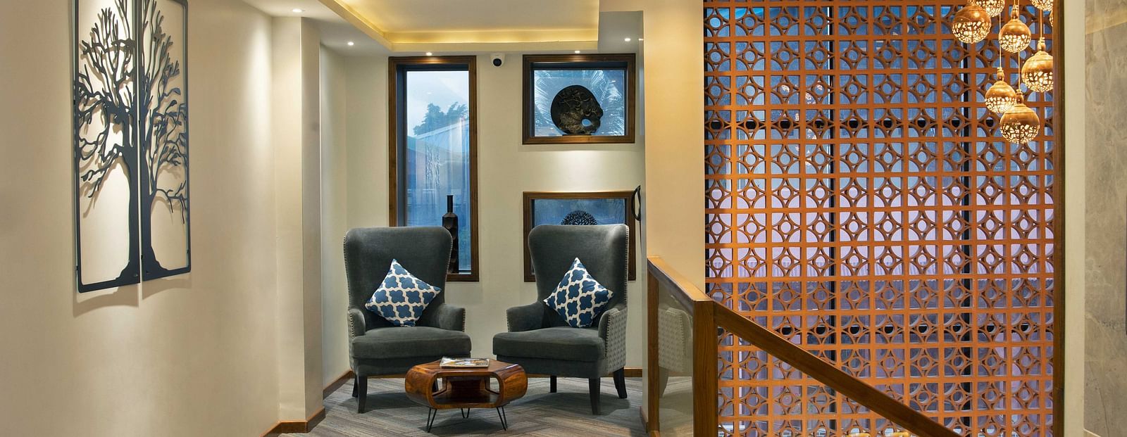 A lounge area at Coral Reef Hotel and Spa in Port Blair featuring two one seater couches placed next to each other and an ottoman on the floor