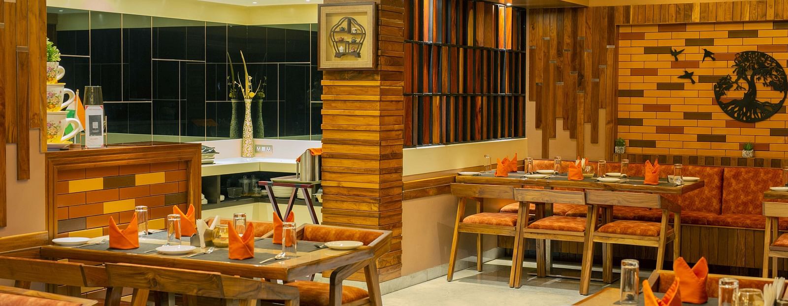 Image of the interiors of Honeycomb Restaurant at Coral Reef Hotel & Spa in Port Blair under warm lighting and walnut furniture 