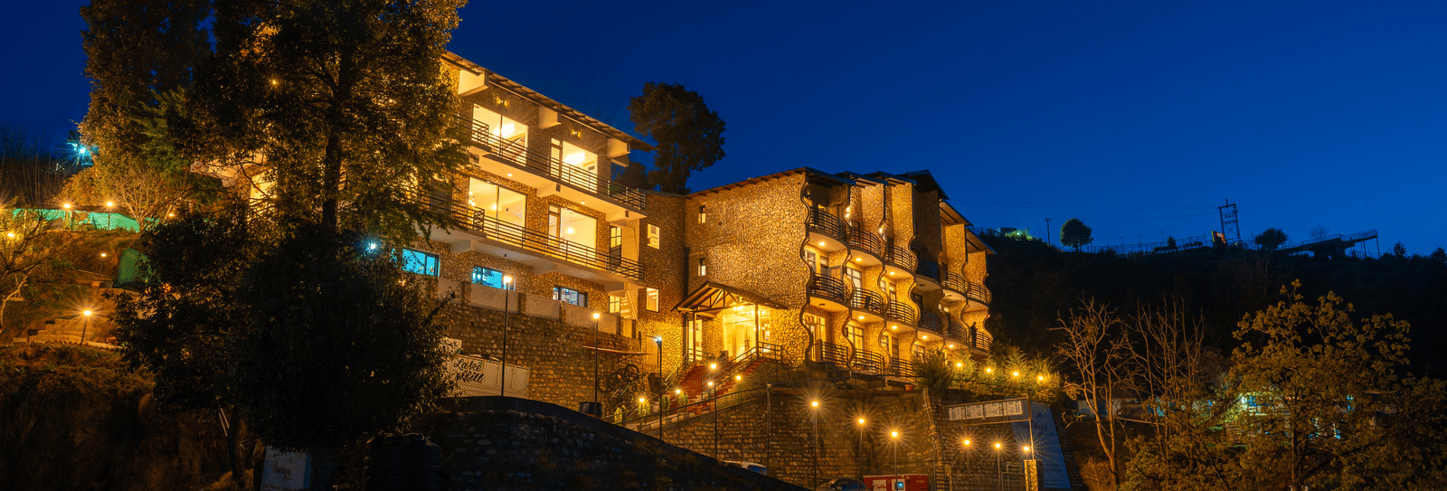 Himalayas Resort By The Lake Hill, Mukteshwar beautifully lit up against a dark blue night sky.
