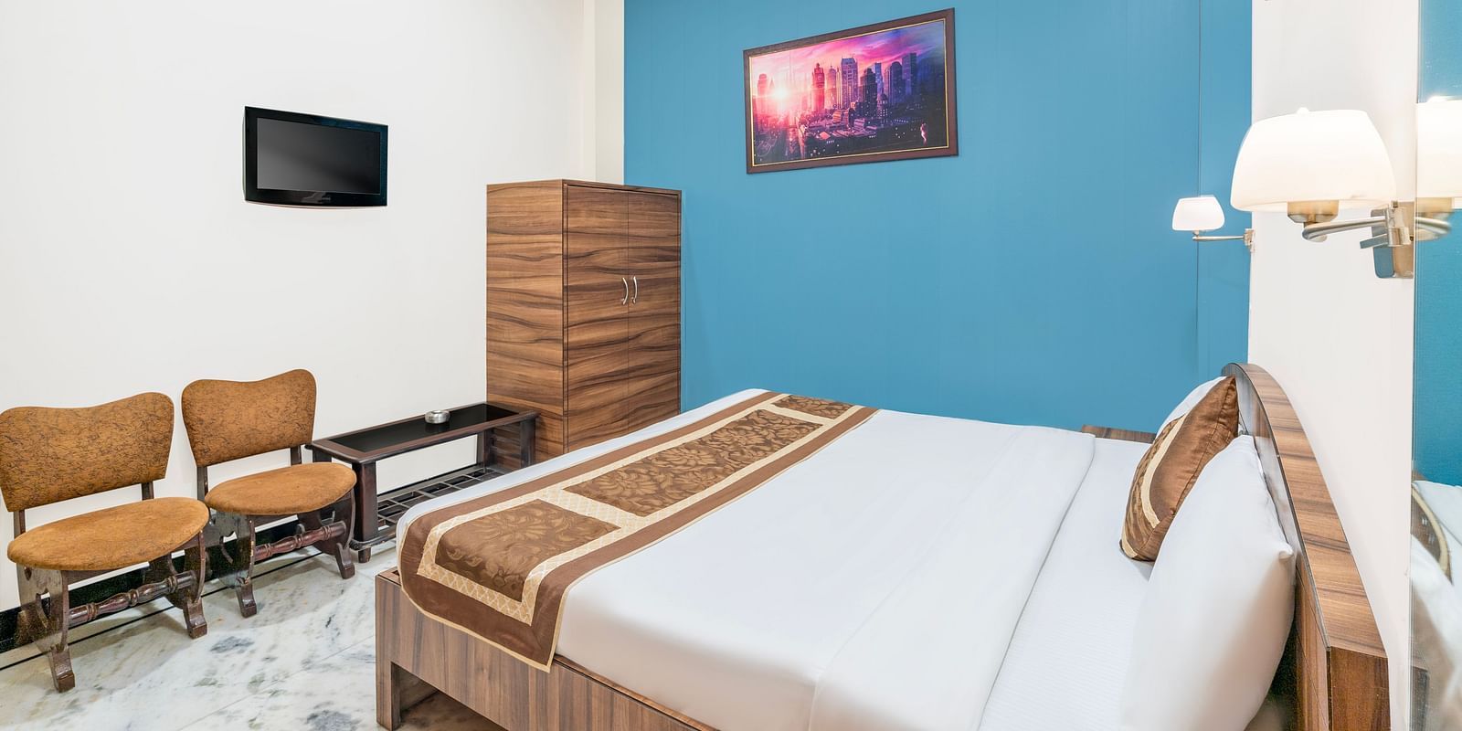 A head-on view of the bedroom at Hotel Moti Palace, featuring a comfy bed, a cupboard, and bedside lighting, creating a welcoming ambiance.