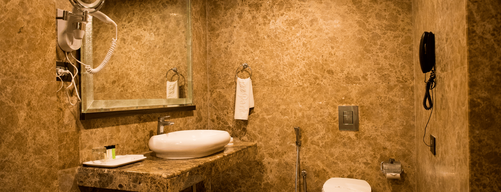 A modern bathroom at Benzz Park Chennai with a single vanity, a toilet, and textured walls.