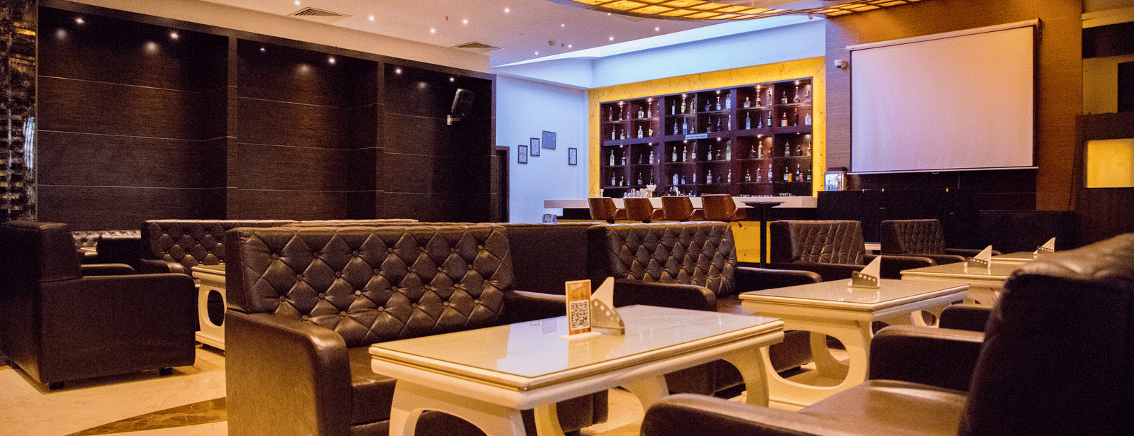Full view of the dining area at the Benzz Park, Vellore, with warm lighting featuring tufted couch.