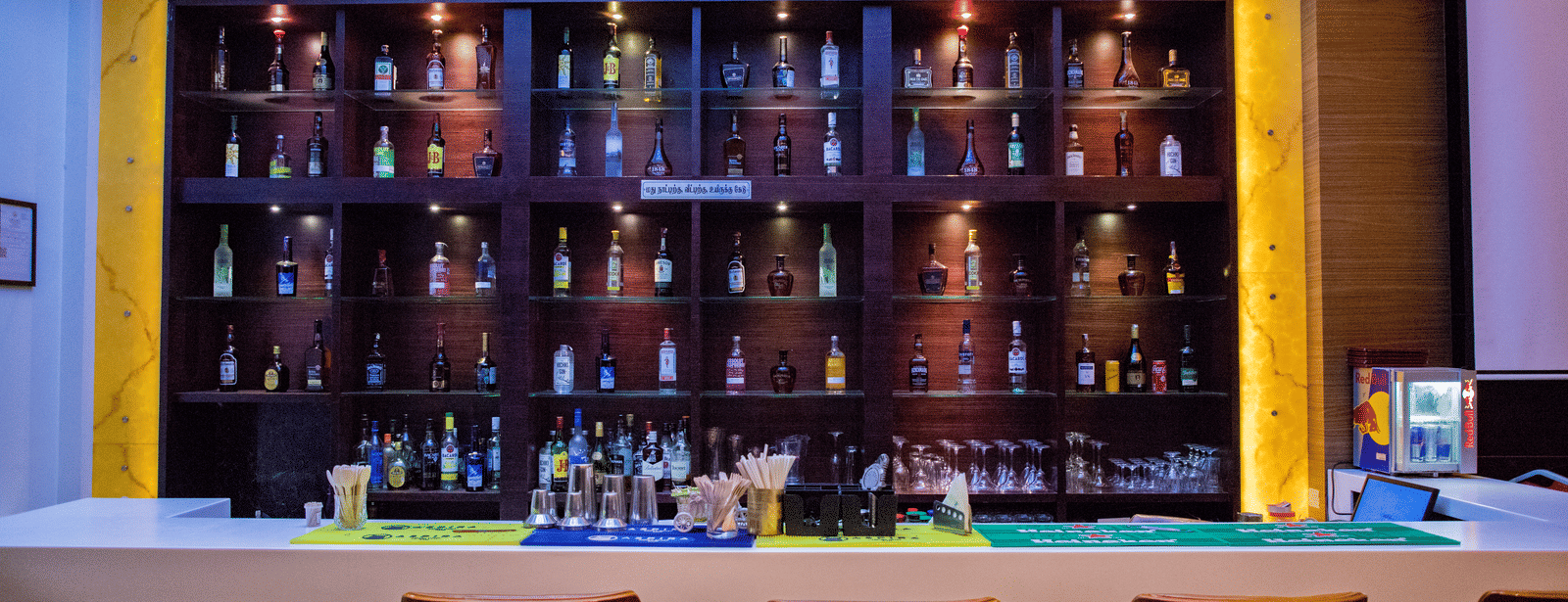 Front view shot of the bar area with an assortment of premium liquor bottles on display behind the bar counter at Benzz Park, Vellore.