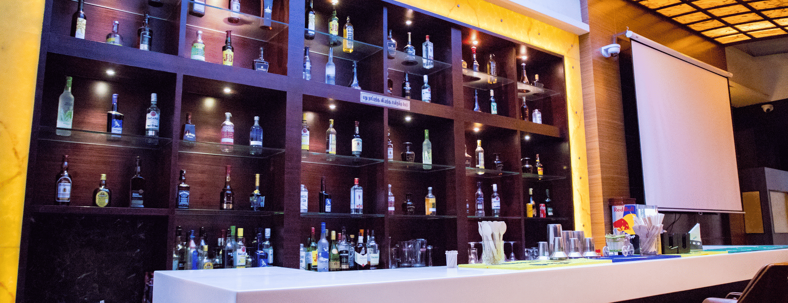 Side view of the bar featuring the bar counter and a display cabinet stacked with various liquor bottles on display at Benzz Park, Vellore.