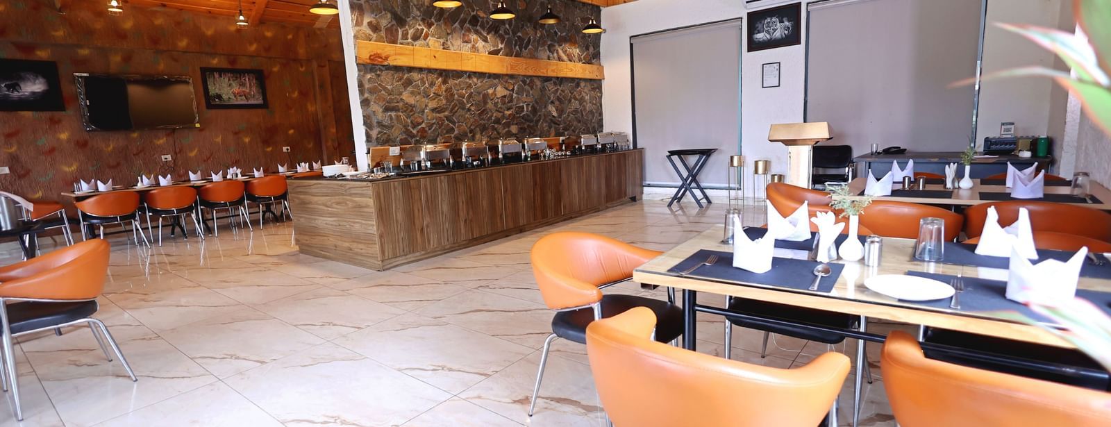 Restaurant with wooden ceiling, stone walls, and modern seating at Corbett Nirvana Resort.