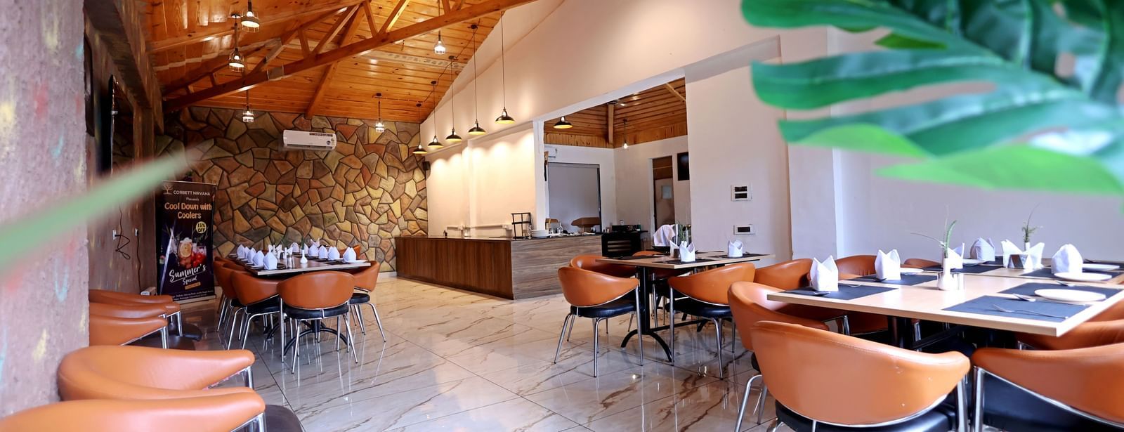 Stylish restaurant with high wooden ceiling and elegant decor at Corbett Nirvana Resort.