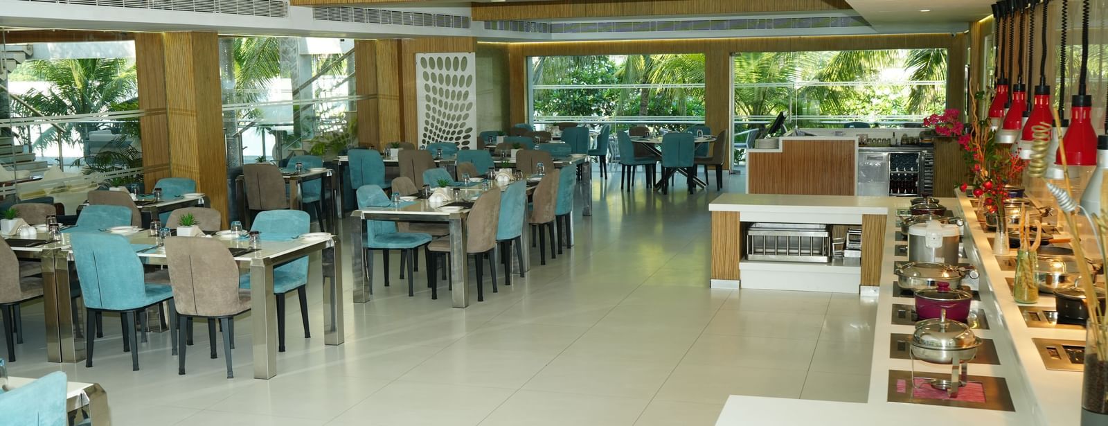 Restaurant seating area with rows of tables and blue chairs beside large windows at Grande Bay Resort & Spa.