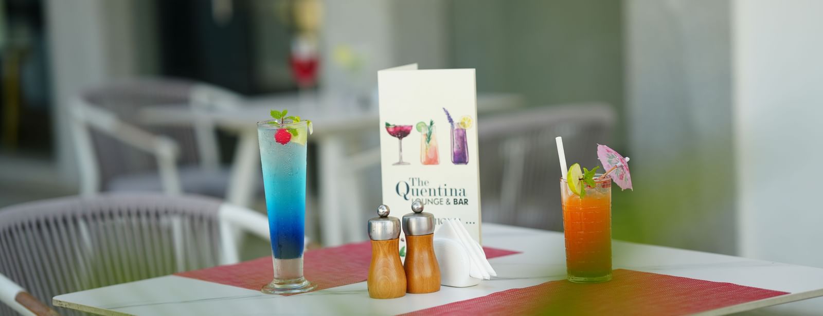 Drinks and menu card placed on an outdoor dining table with chairs at Grande Bay Resort & Spa.