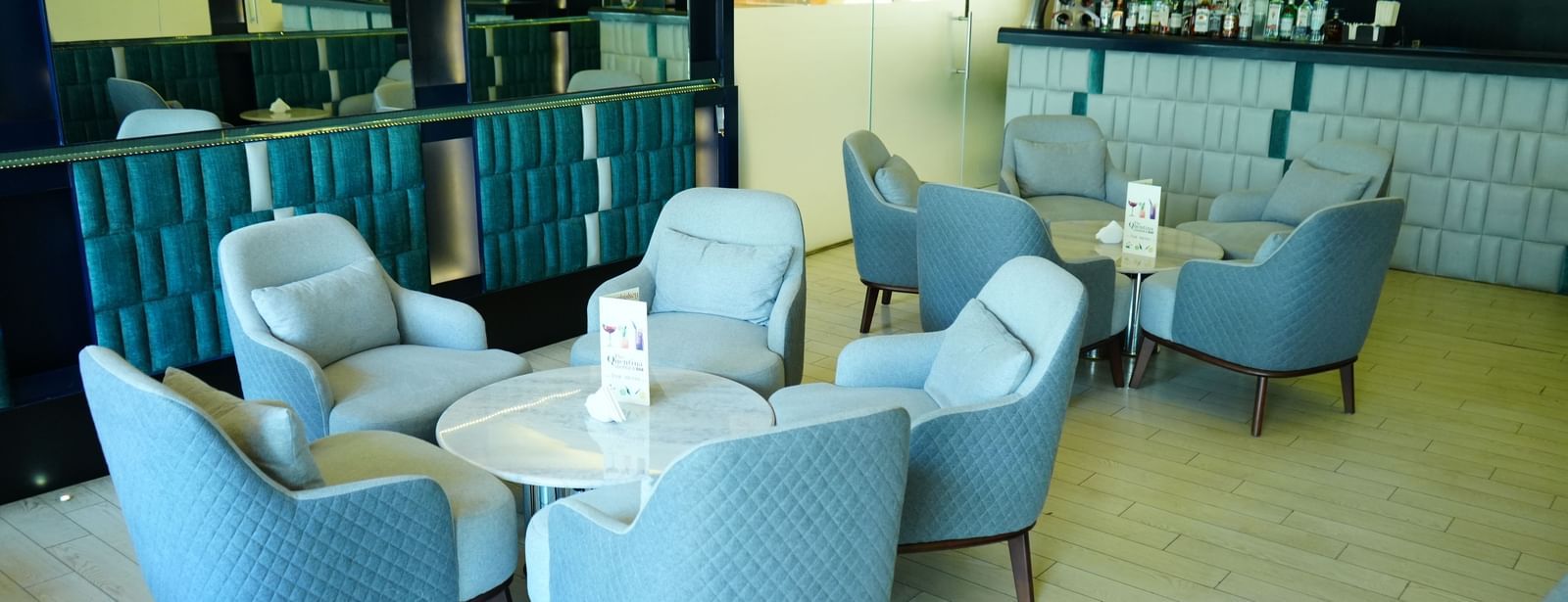 Lounge seating with armchairs and tables beside large glass windows at Grande Bay Resort & Spa.