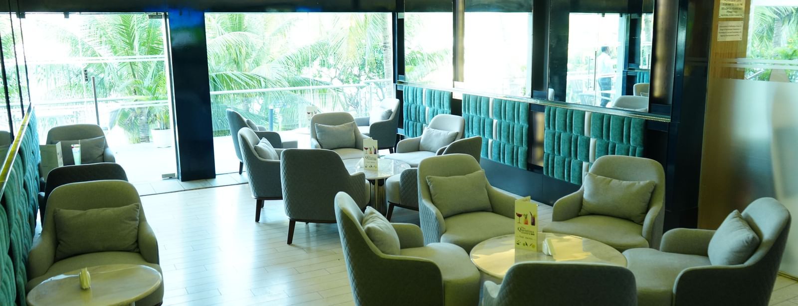 Indoor lounge area with armchairs and tables arranged in rows at Grande Bay Resort & Spa.