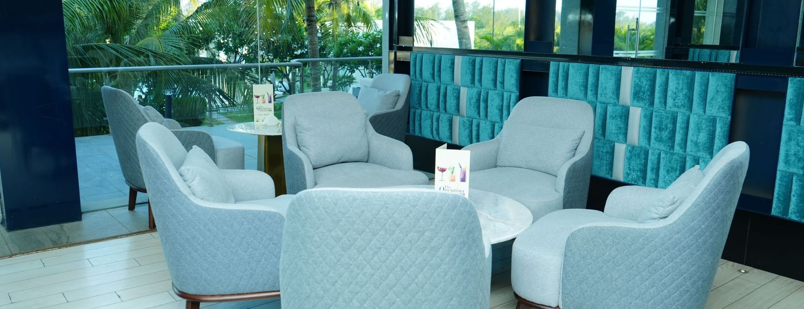 Indoor seating area with armchairs and tables beside large windows at Grande Bay Resort & Spa.
