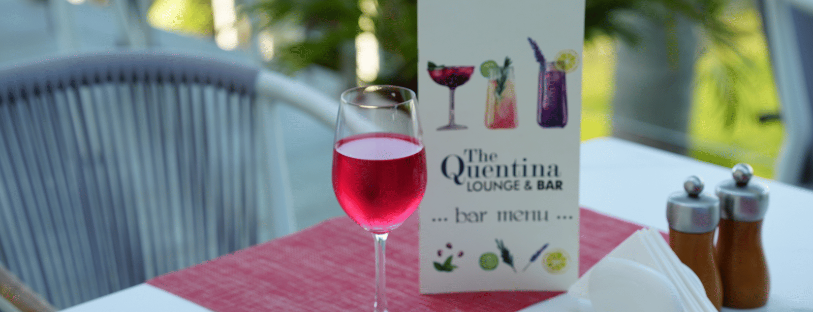 Outdoor table at The Quentina Bar showcasing a red cocktail and menu card - Grande Bay Resort & Spa, Mamallapuram