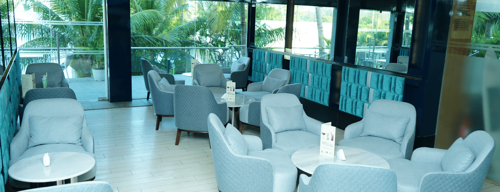 Spacious seating layout inside The Quentina Bar with multiple modern chair arrangements and bright natural light - Grande Bay Resort & Spa, Mamallapuram