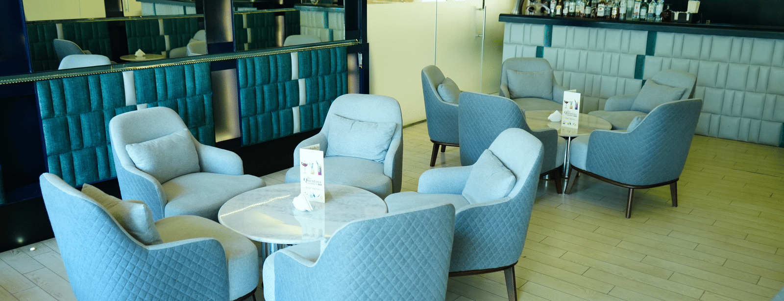 A stylish seating area inside The Quentina Bar featuring cushioned chairs, modern decor, and a bar counter in the backdrop - Grande Bay Resort & Spa, Mamallapuram