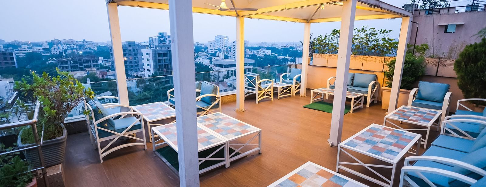 An outdoor dining setup at Hotel Ashok Nagpur featuring cushioned chairs and tables arranged on a rooftop or terrace.
